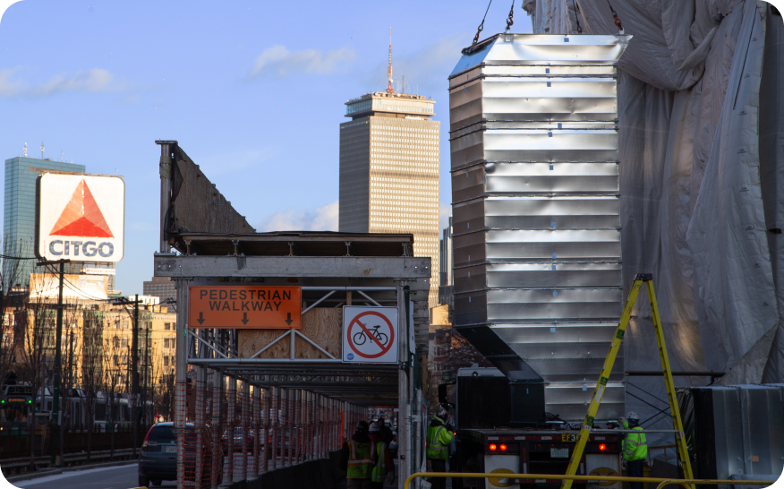overlooking boston with prudential building and citgo sign with ductwork being loading by crane